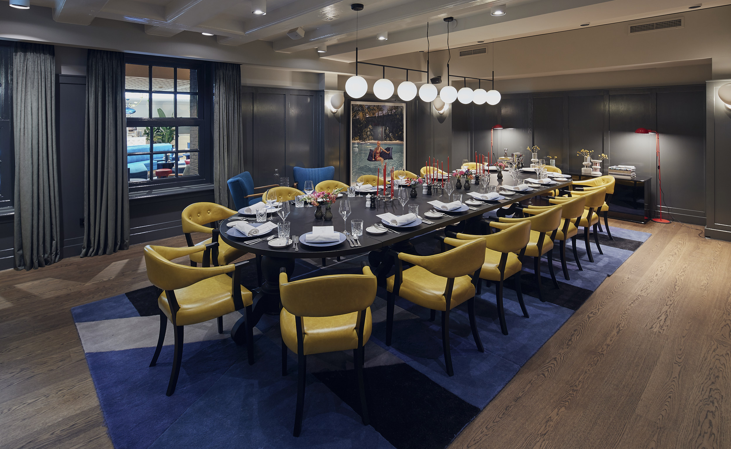 Long table set with glassware in front of yellow curtains