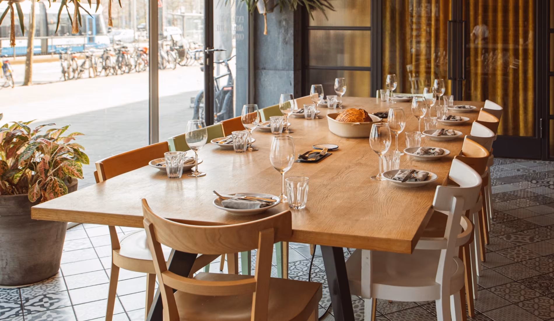 Long table set with glassware in front of yellow curtains