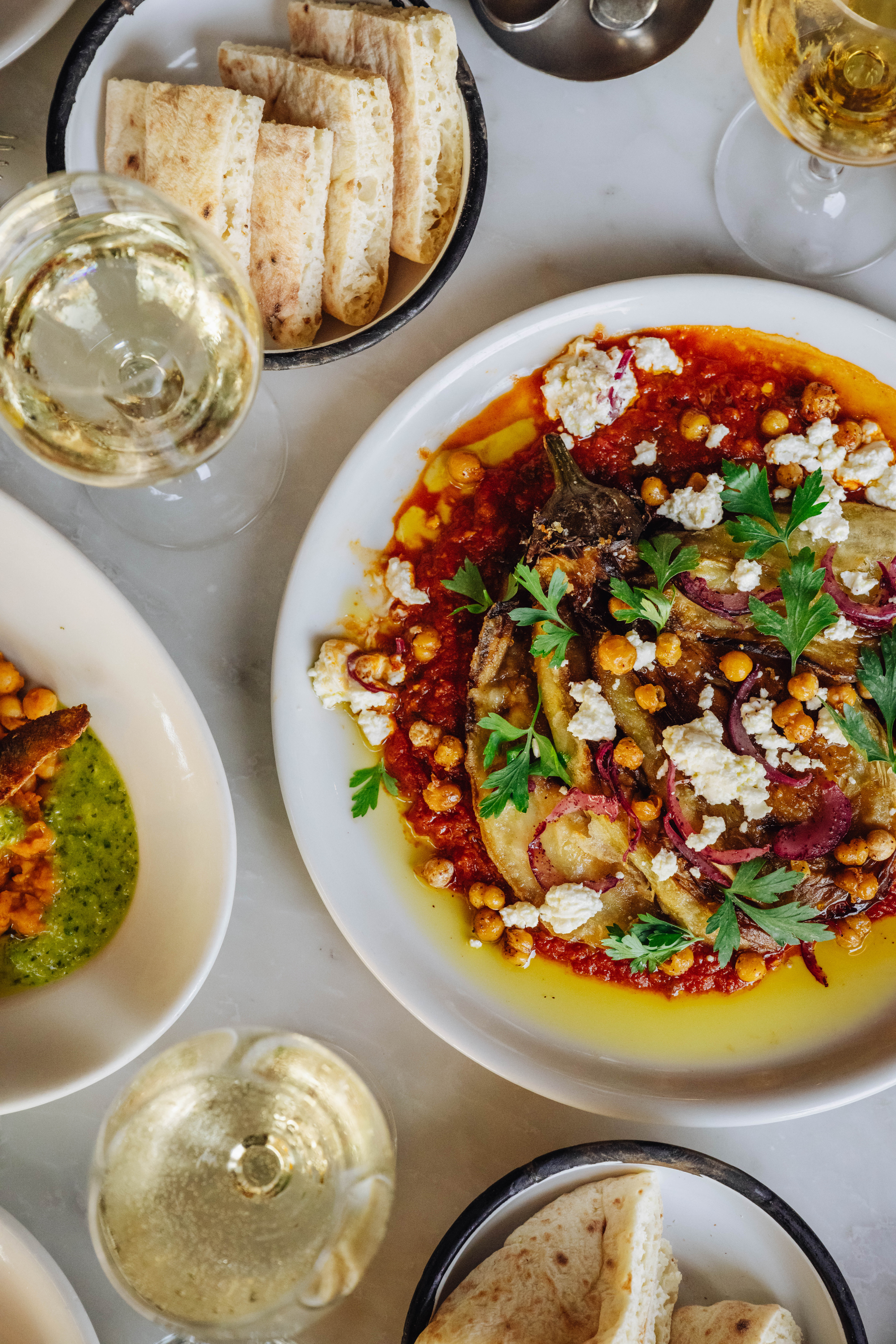 Two plates of lunch dishes with green sauce and salad