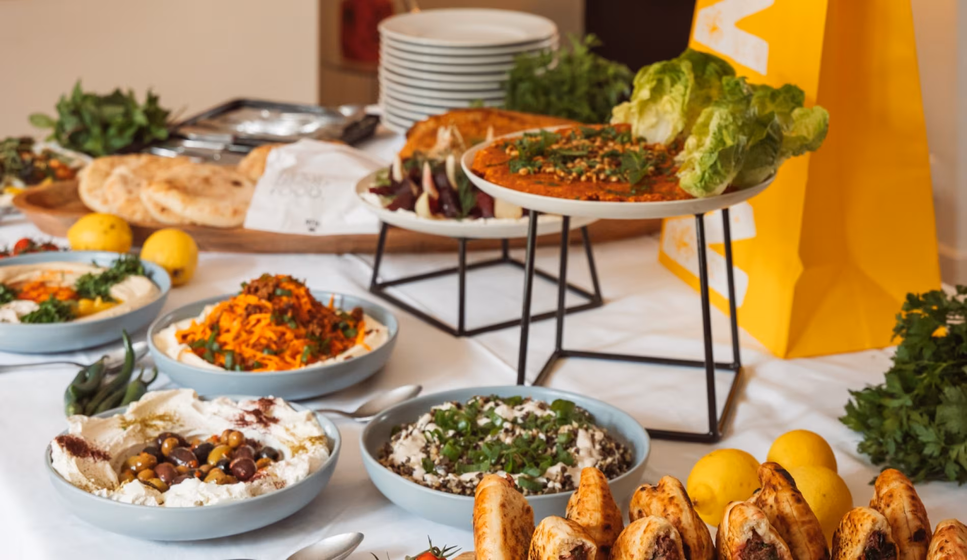 Buffet arrangement of salads, dips and bread on stands with a yellow napkin