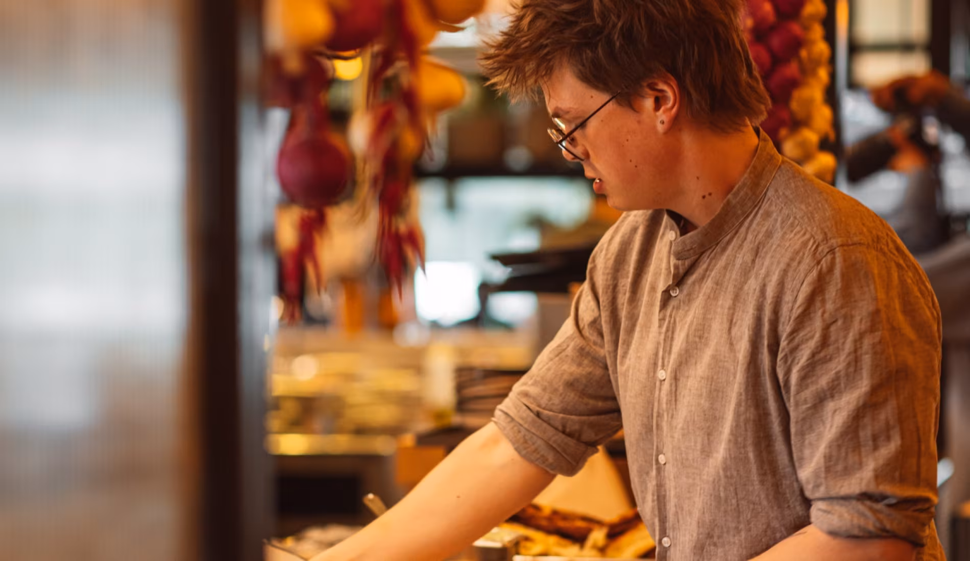 Chef plating a dish behind the counter at NENI Amsterdam