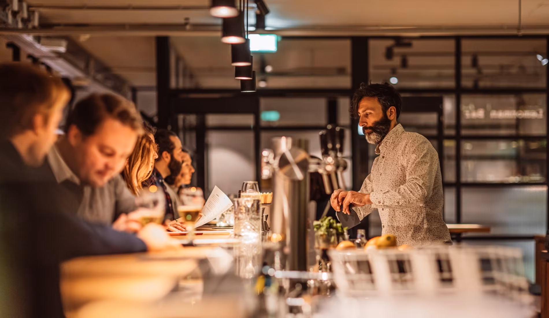 Guests seated at the bar being served by a bartender