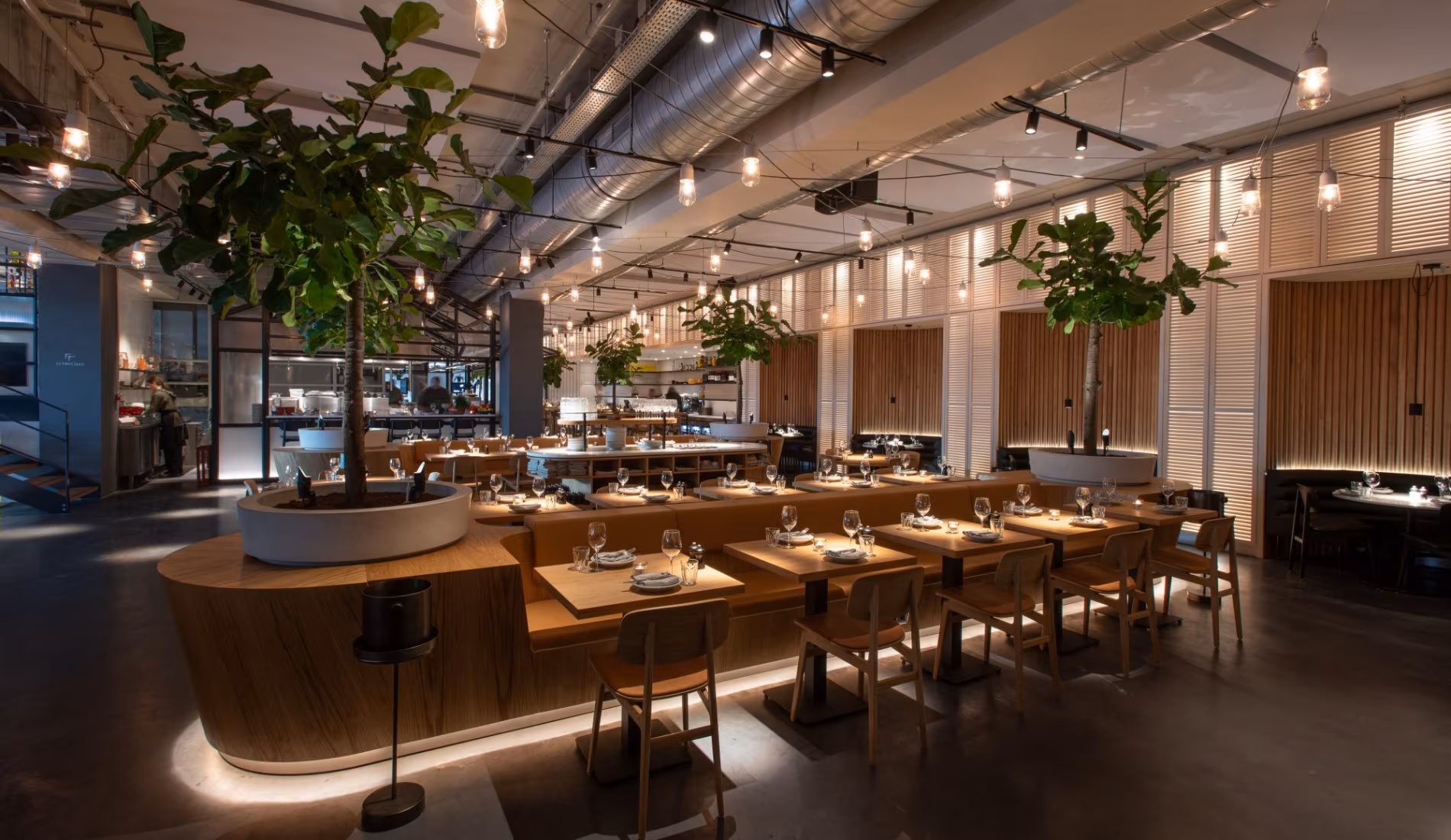 Long tables and the open kitchen counter framed by hanging plants