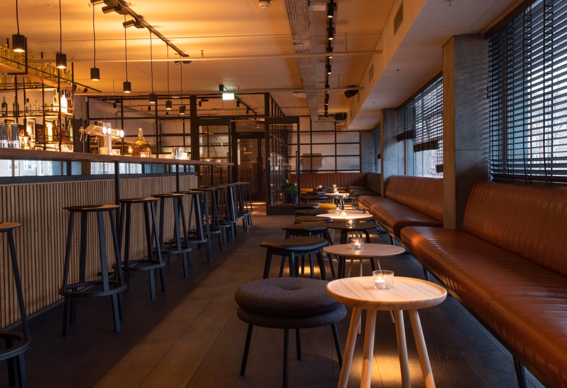 Bar stools, leather banquette seating and warm pendant lighting in NENI Amsterdam