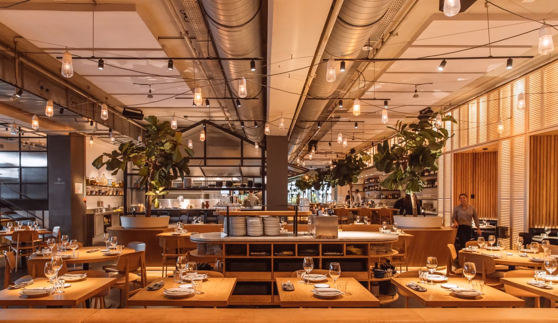 Wide view of the NENI Amsterdam dining room with tables and plants