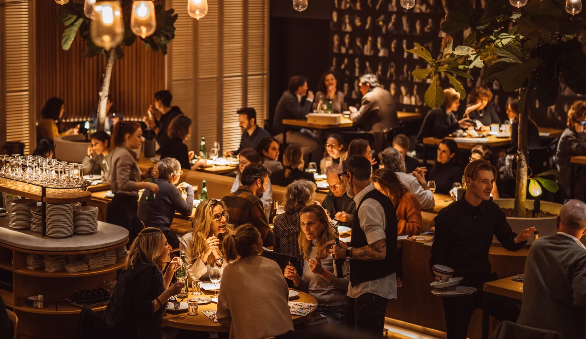 Full dining room at NENI Amsterdam with guests seated under hanging lanterns