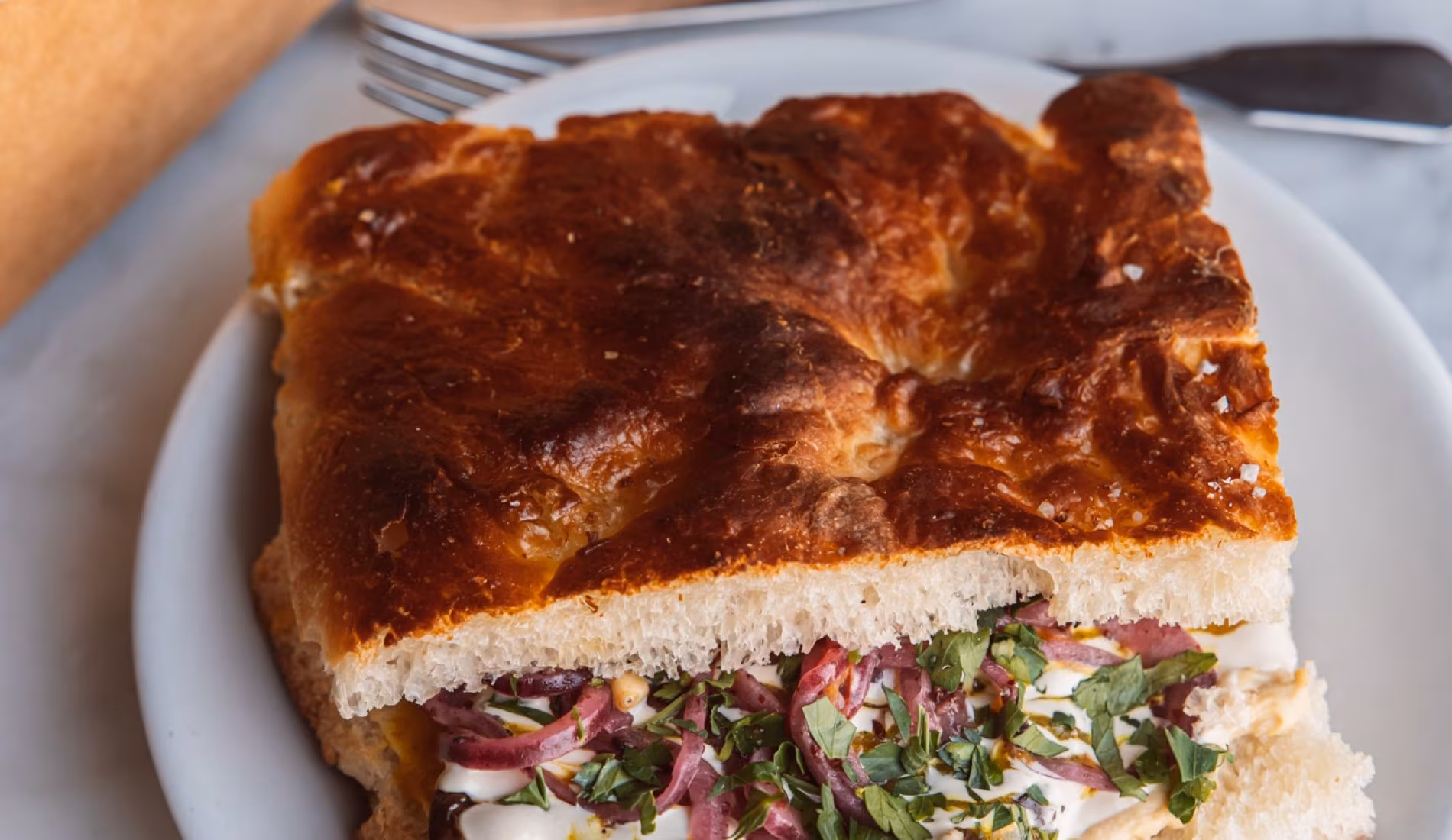 Focaccia sandwich filled with vegetables and herbs on a plate