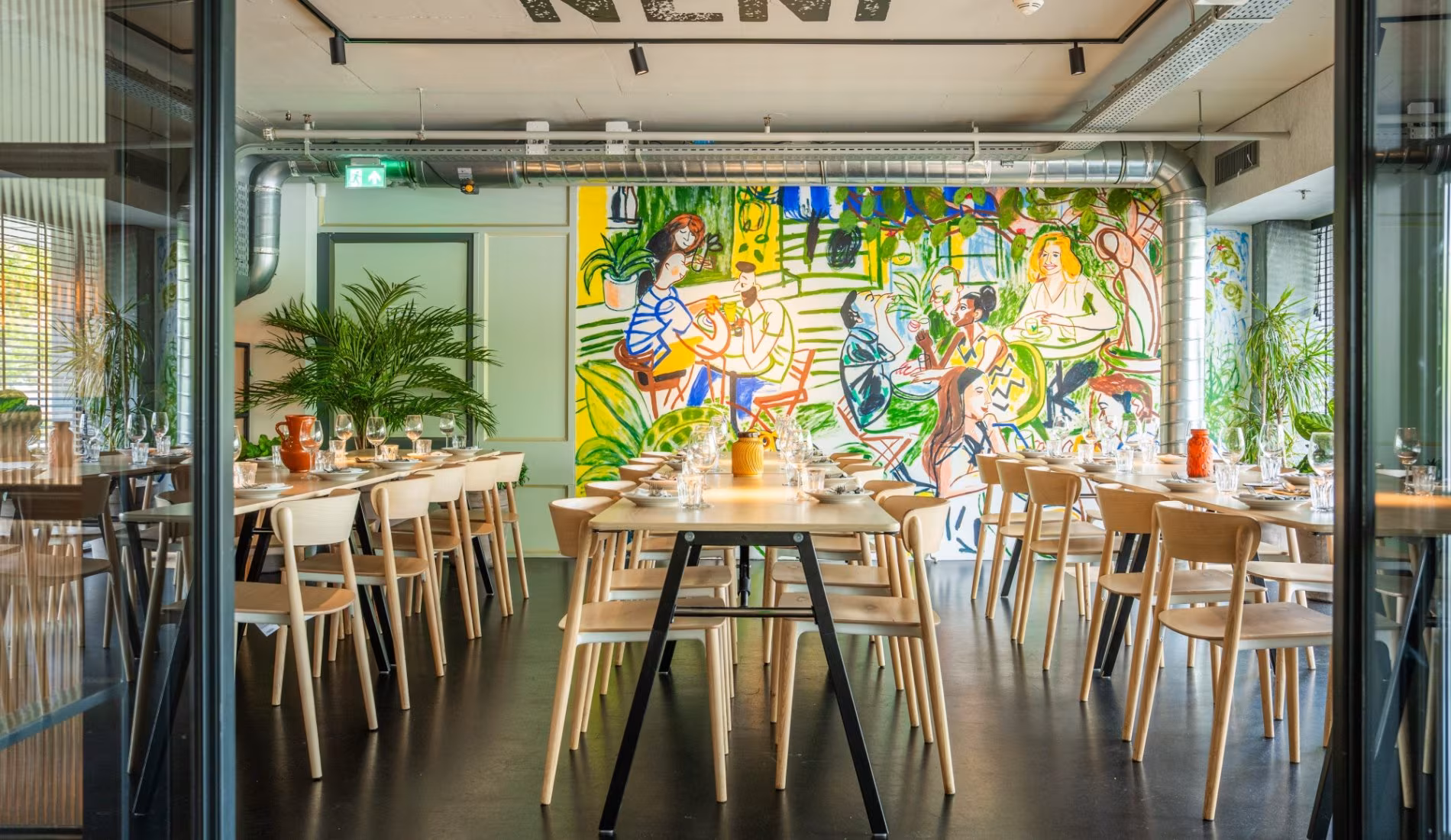 Long table beside the glass wall with the colourful mural behind it
