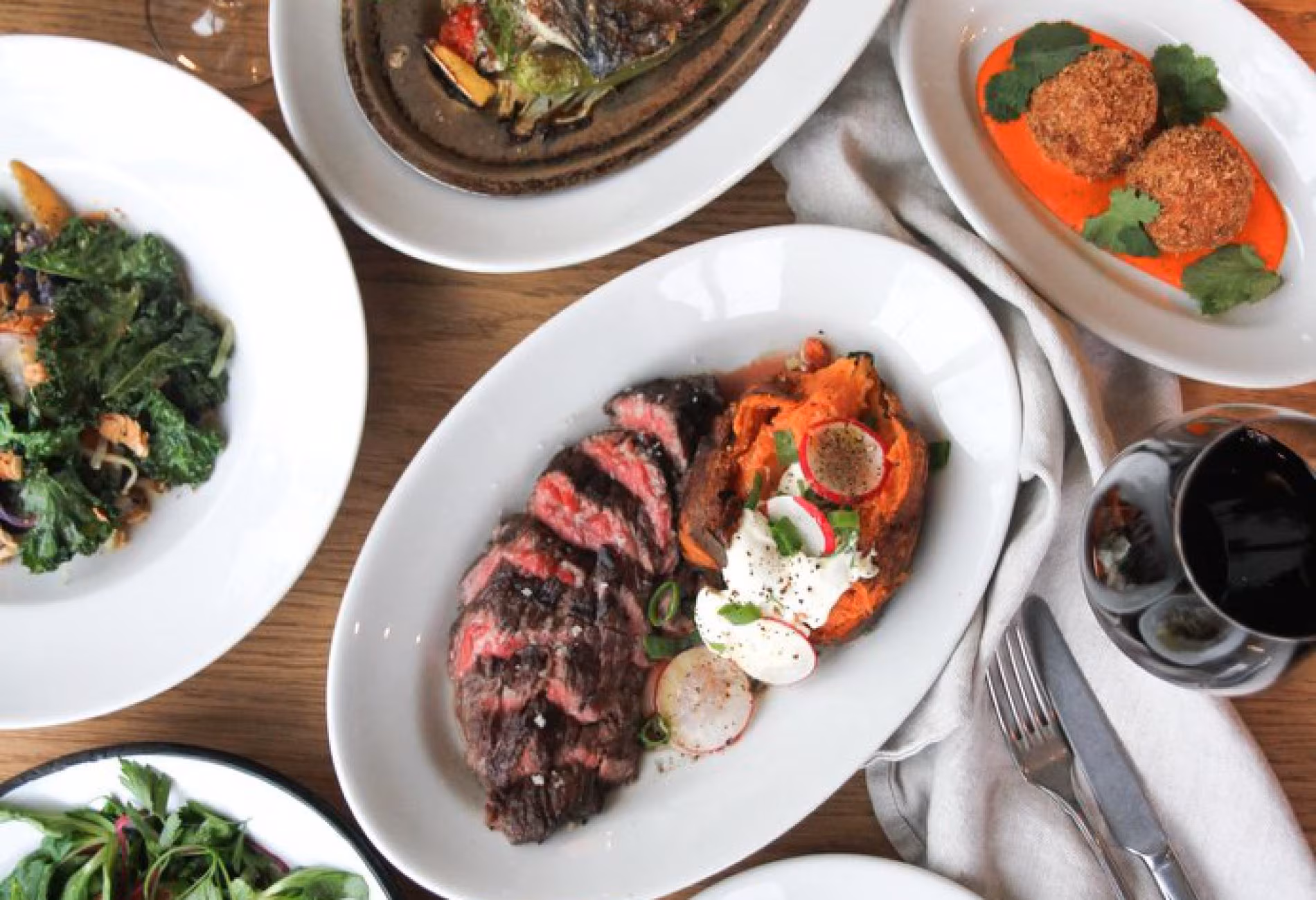 Plates of grilled meat and vegetables with side dishes