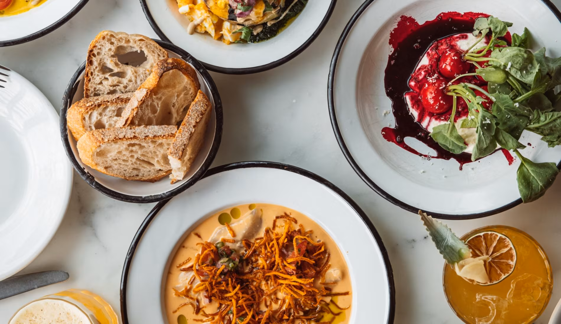 Table with bread, salads and a plate of pasta seen from above