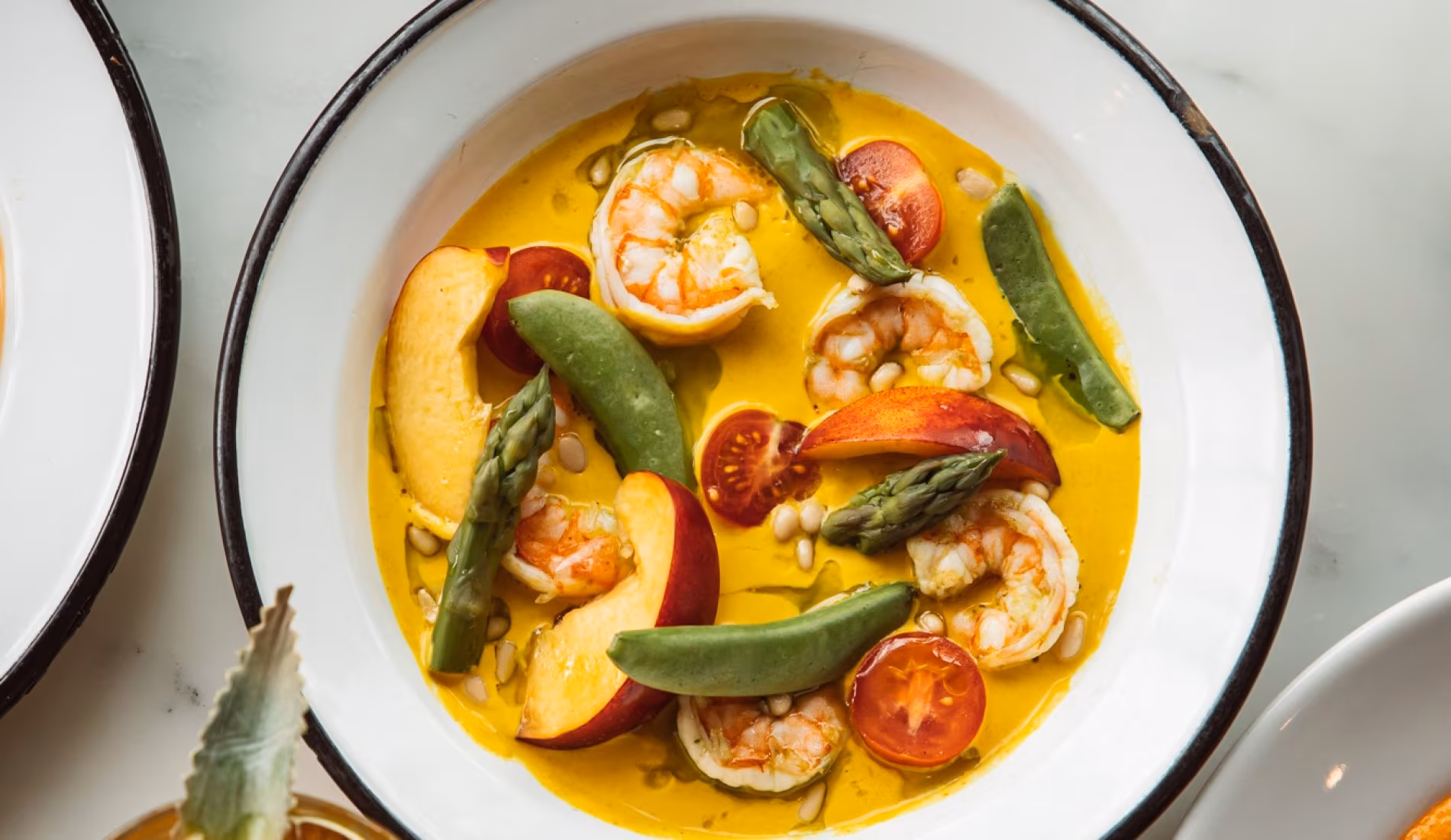 Plate of fish in a saffron sauce with green peppers and tomatoes