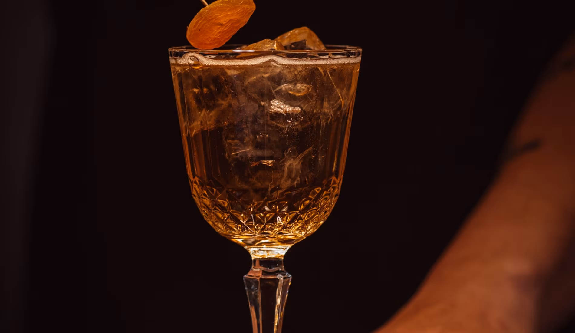 Amber cocktail in a stemmed glass garnished with a dried citrus slice