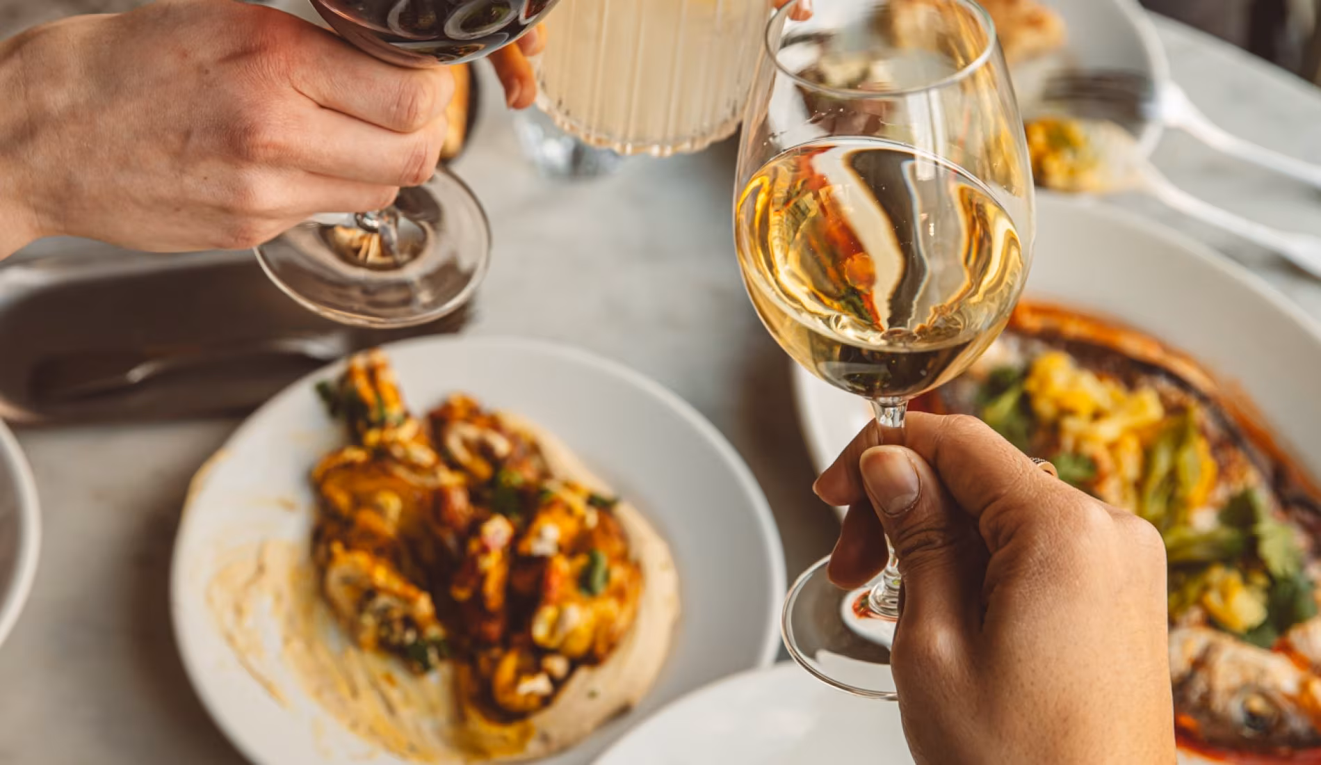 Guests eating a main course with a glass of white wine