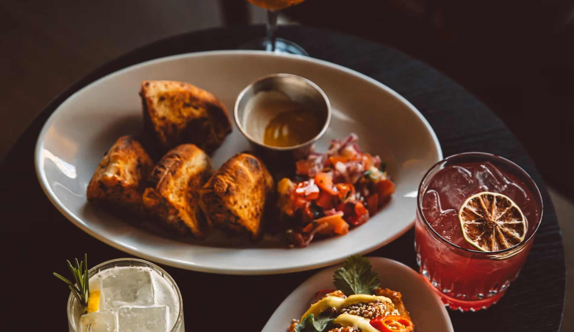Plate of roasted parcels with tomato relish beside a red cocktail