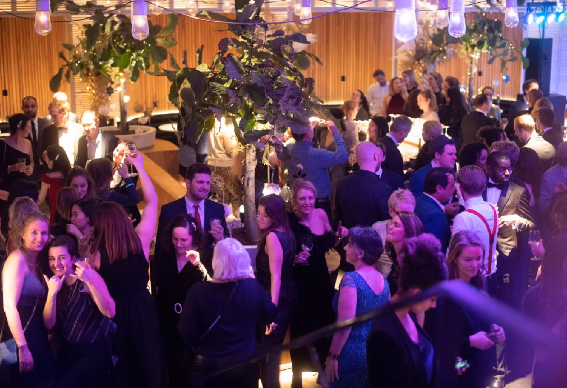 Crowd dancing under purple lighting during an event at NENI Amsterdam