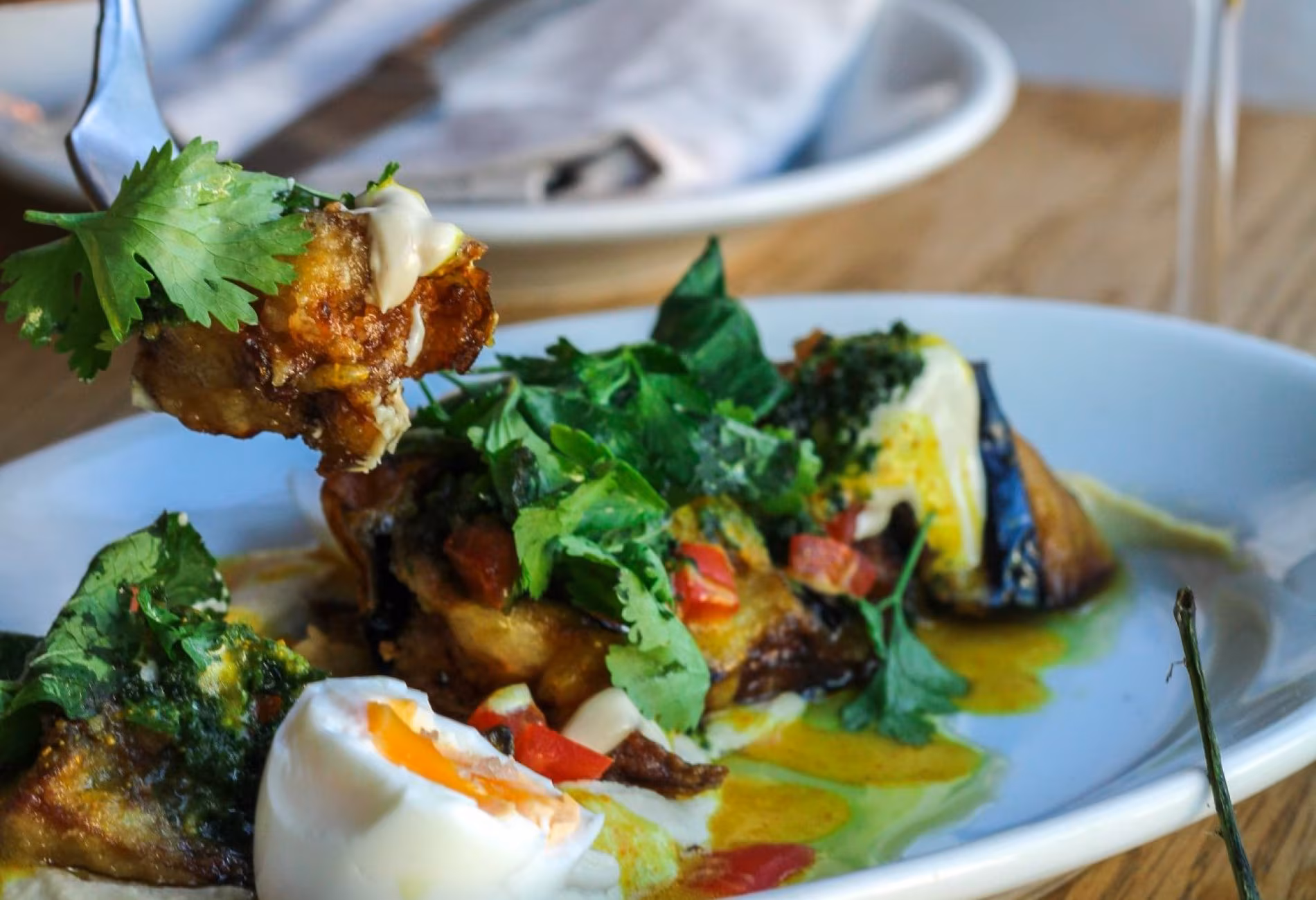 Plate of roasted vegetables topped with a poached egg and herbs