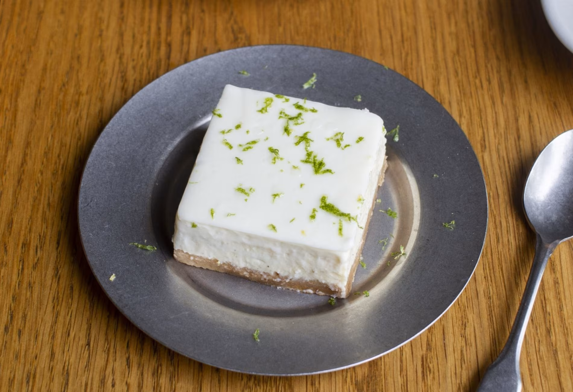 Slice of cheesecake with lime zest on a grey plate