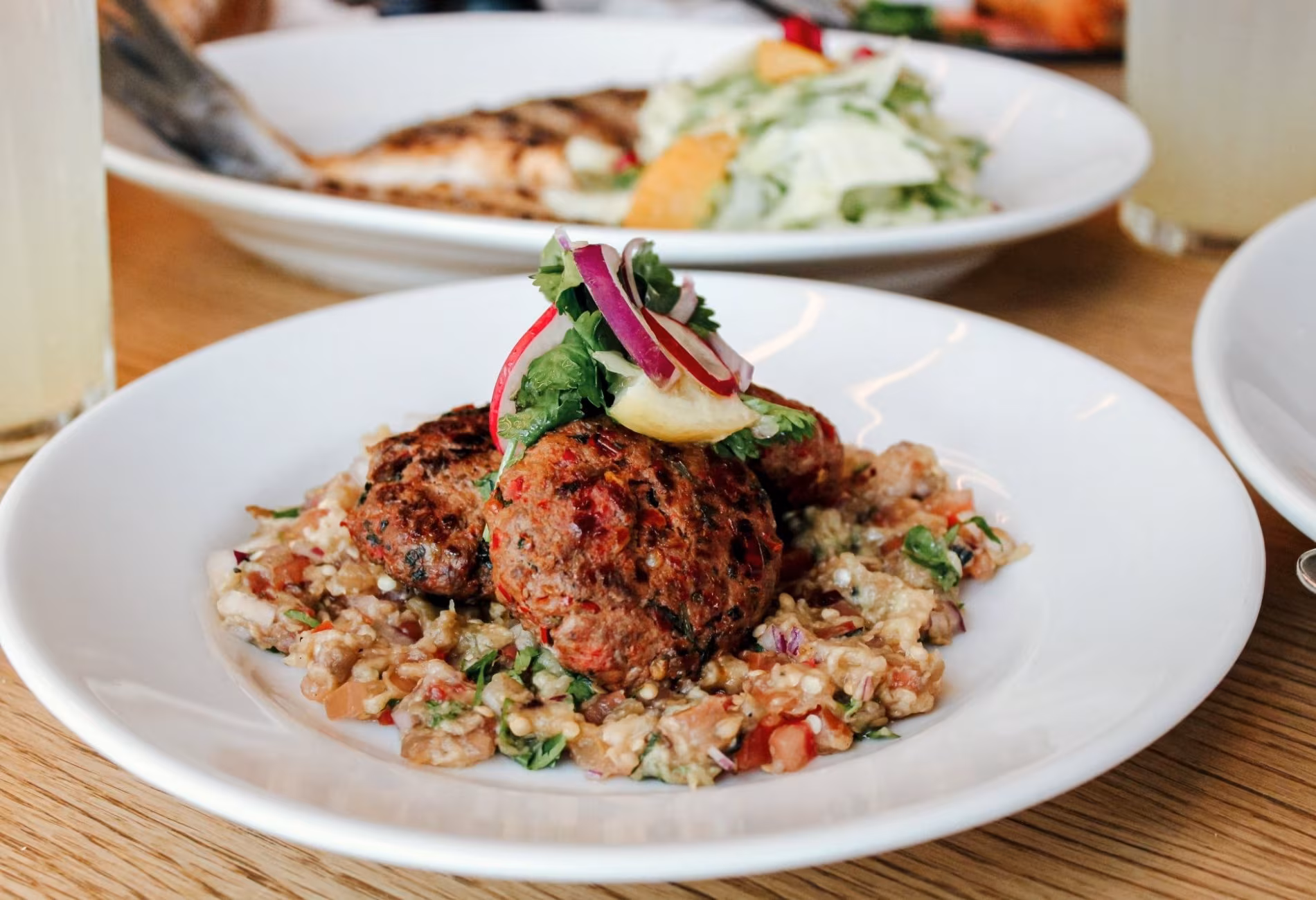 Plated main course of meat on a bed of grains with herbs