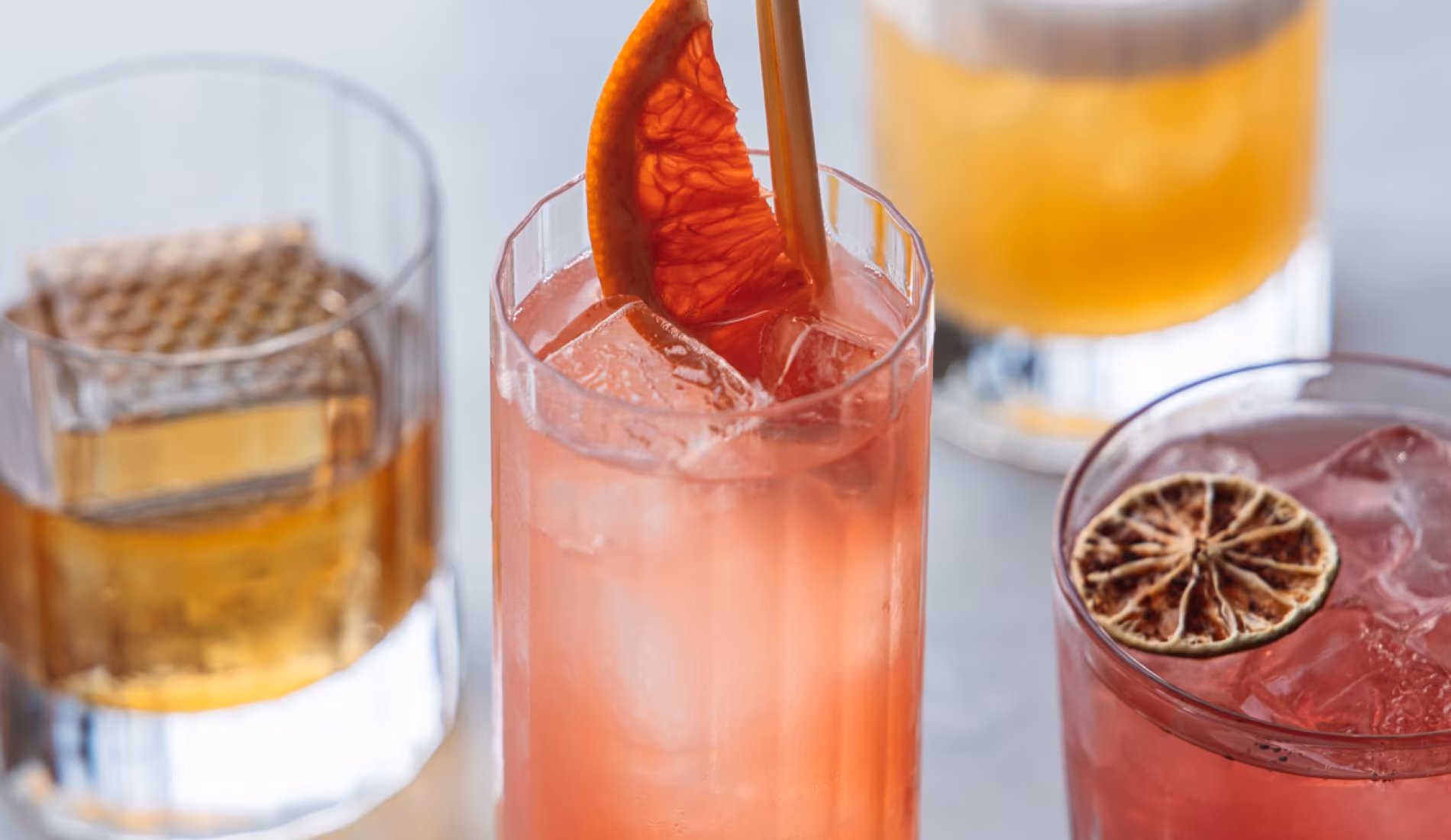 Three cocktails in tumblers on the bar