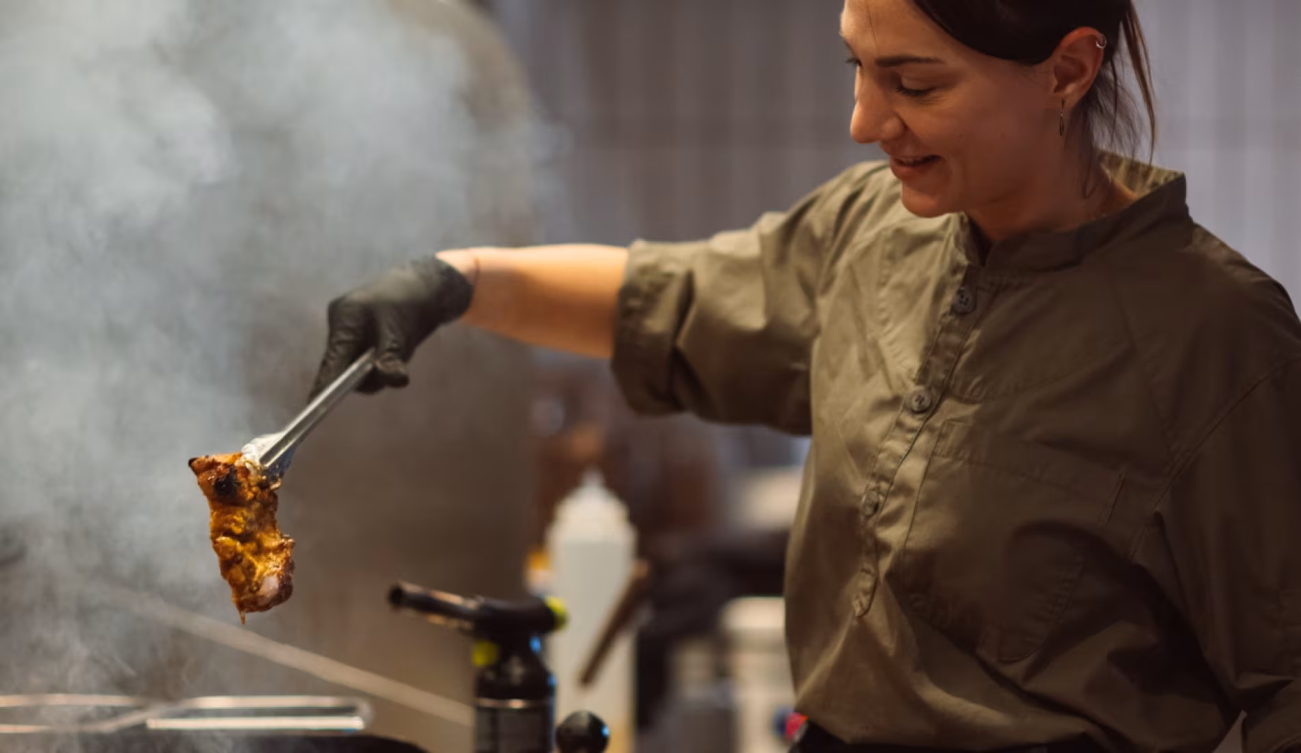 Chef lifting food from the grill in the open kitchen