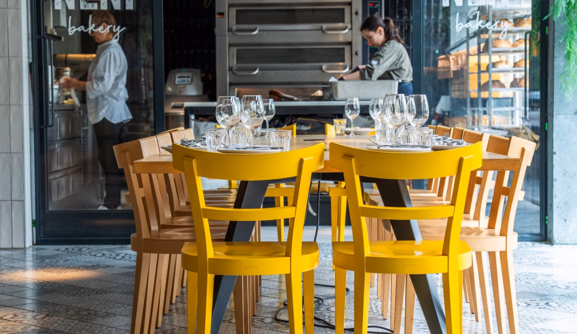 Yellow chairs and set tables beside the open kitchen at NENI Amsterdam