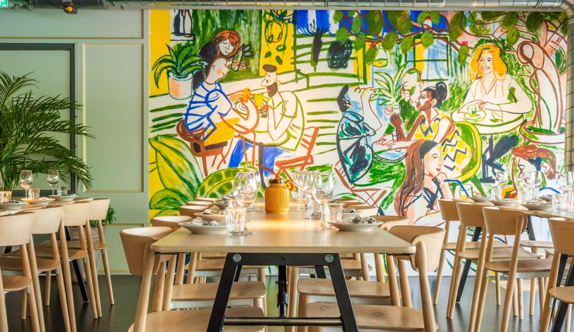 Table set for a group in front of the colourful mural wall